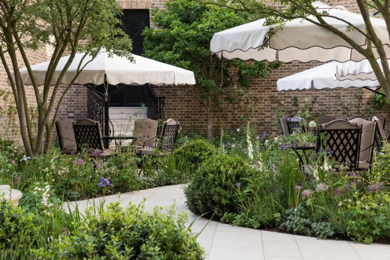 The Secret Garden, with white parasols over tables among planting and brick walls, The Ritz London