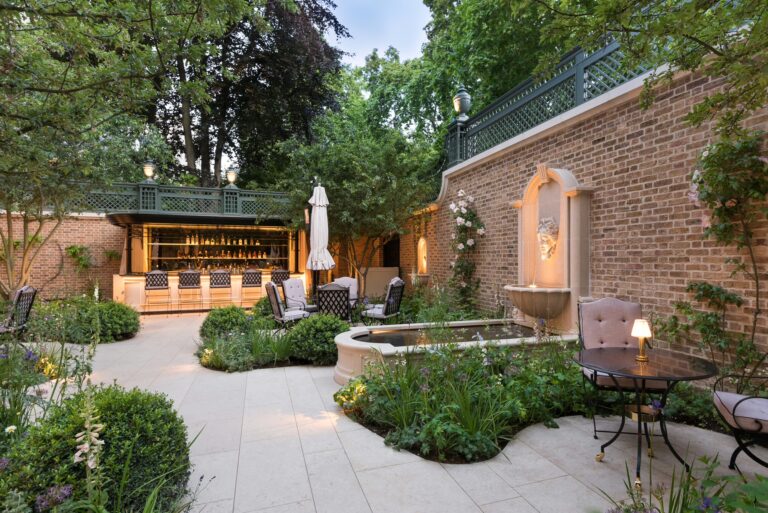 The Secret Garden with a wall fountain, paved paths and the garden bar beyond, The Ritz London
