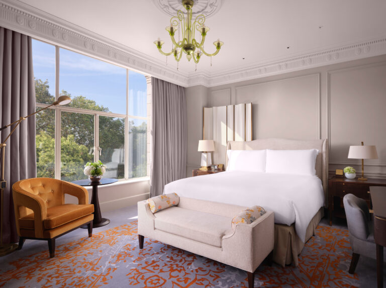 A bedroom with a king bed and a window onto the trees of Embankment Gardens, The Savoy