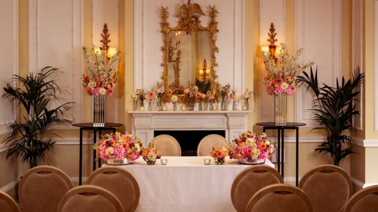 Chairs arranged before a flower-dressed table and marble fireplace for a small ceremony, The Savoy