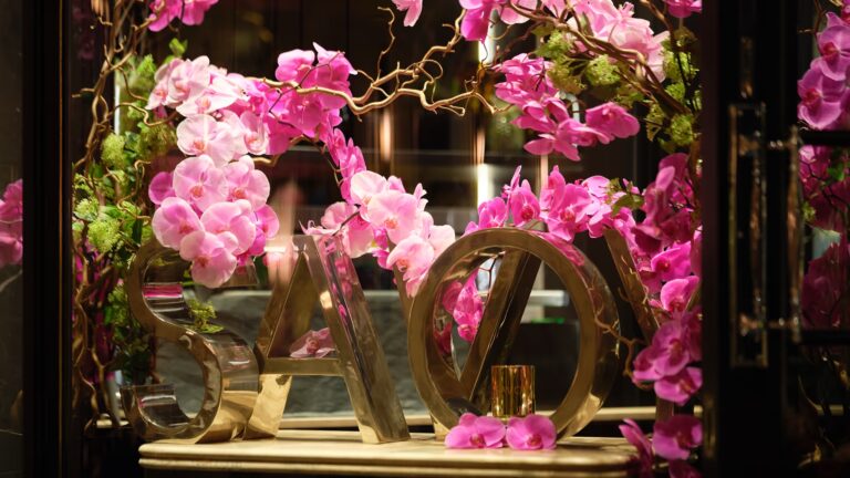 Pink orchids arranged around gilded letters spelling Savoy, The Savoy