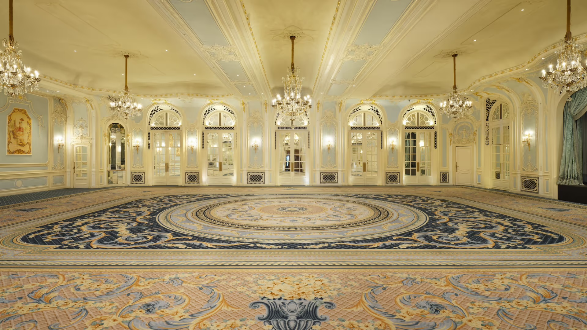 The Lancaster Ballroom empty, with its patterned carpet, crystal chandeliers and arched mirrored doors, The Savoy