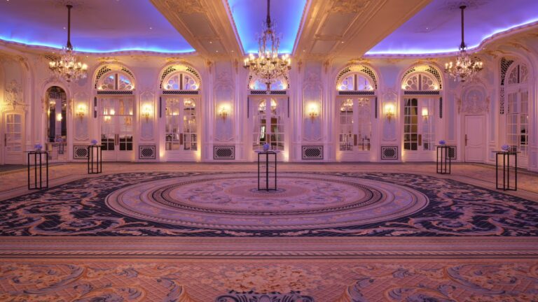 The Lancaster Ballroom lit in blue and gold, with its central carpet and chandeliers, The Savoy