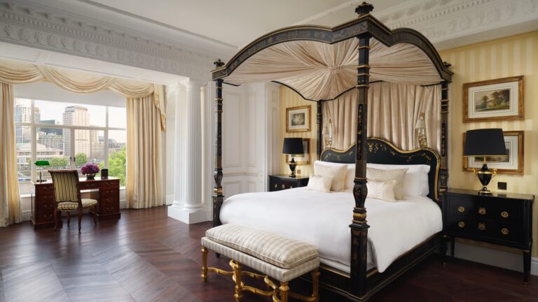 A four-poster bed in a Royal Suite bedroom with windows over the river, The Savoy