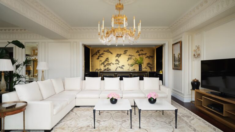 A Royal Suite sitting room with white sofas, a painted screen and river-facing windows, The Savoy