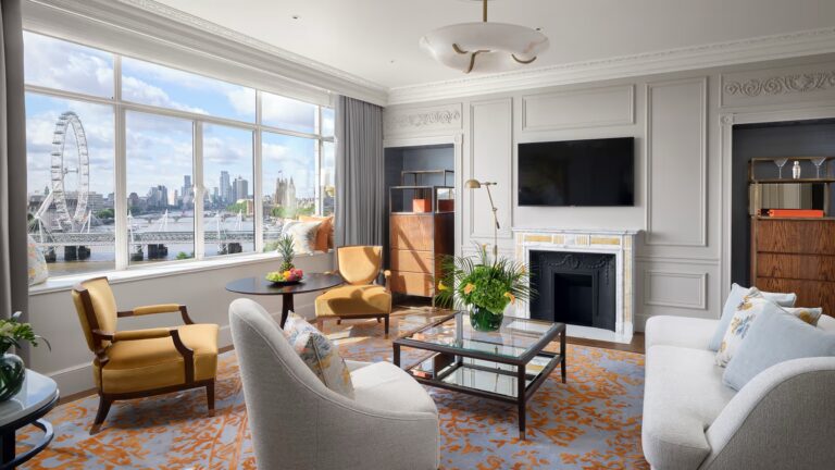 A river view suite sitting room with a fireplace and windows onto the London Eye, The Savoy