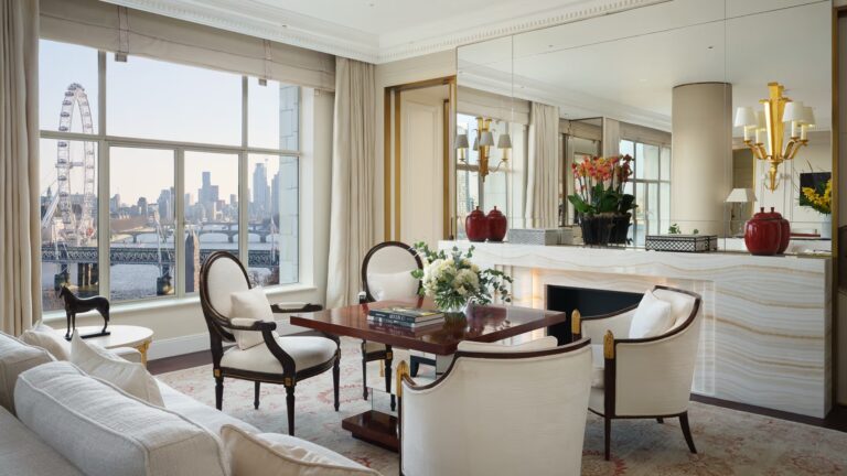 The Savoy Suite living room with a fireplace, a desk and windows onto the Thames, The Savoy