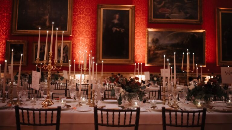 Dinner tables with tall candelabra and flowers in a red-walled gallery hung with paintings, The Wallace Collection
