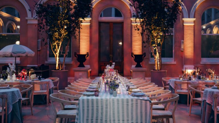 Tables with striped cloths among lit trees and stone urns in the Courtyard at night, The Wallace Collection