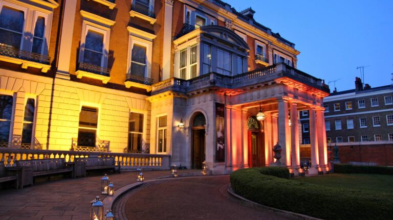 The front of Hertford House lit up at dusk, with lanterns along the drive, The Wallace Collection