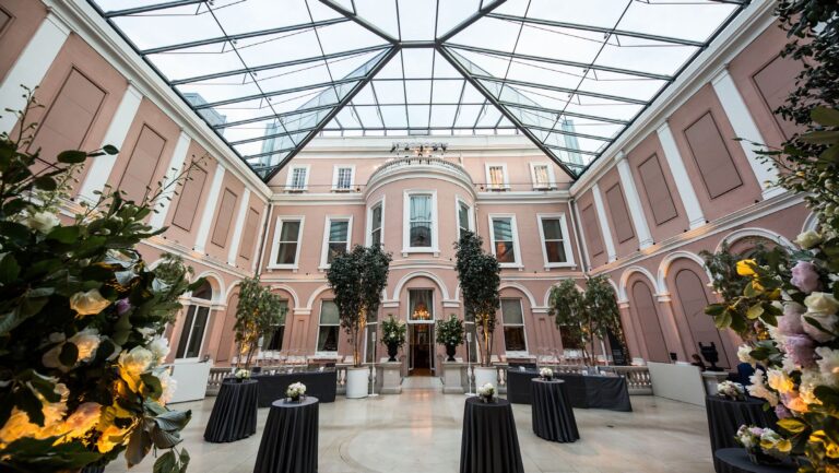 The Courtyard by day, with its glass roof, pink walls, arched windows and potted trees, The Wallace Collection
