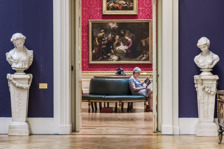 Two marble busts on pedestals framing a view into a red-walled gallery, The Wallace Collection