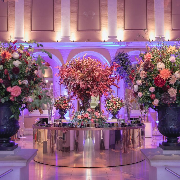 A round central bar banked with flowers in the Courtyard, lit in pink and violet, The Wallace Collection