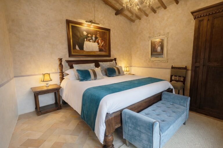 The Vivaldi room with a wooden bed, blue throw and period paintings, Torre Collevento