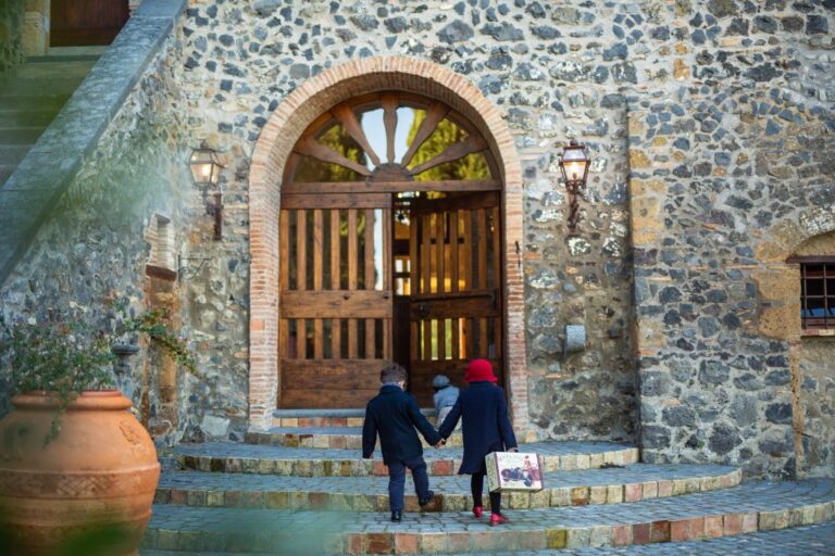 The arched wooden entrance door set in the tower's rubble-stone wall, with steps and terracotta urn, Torre Collevento