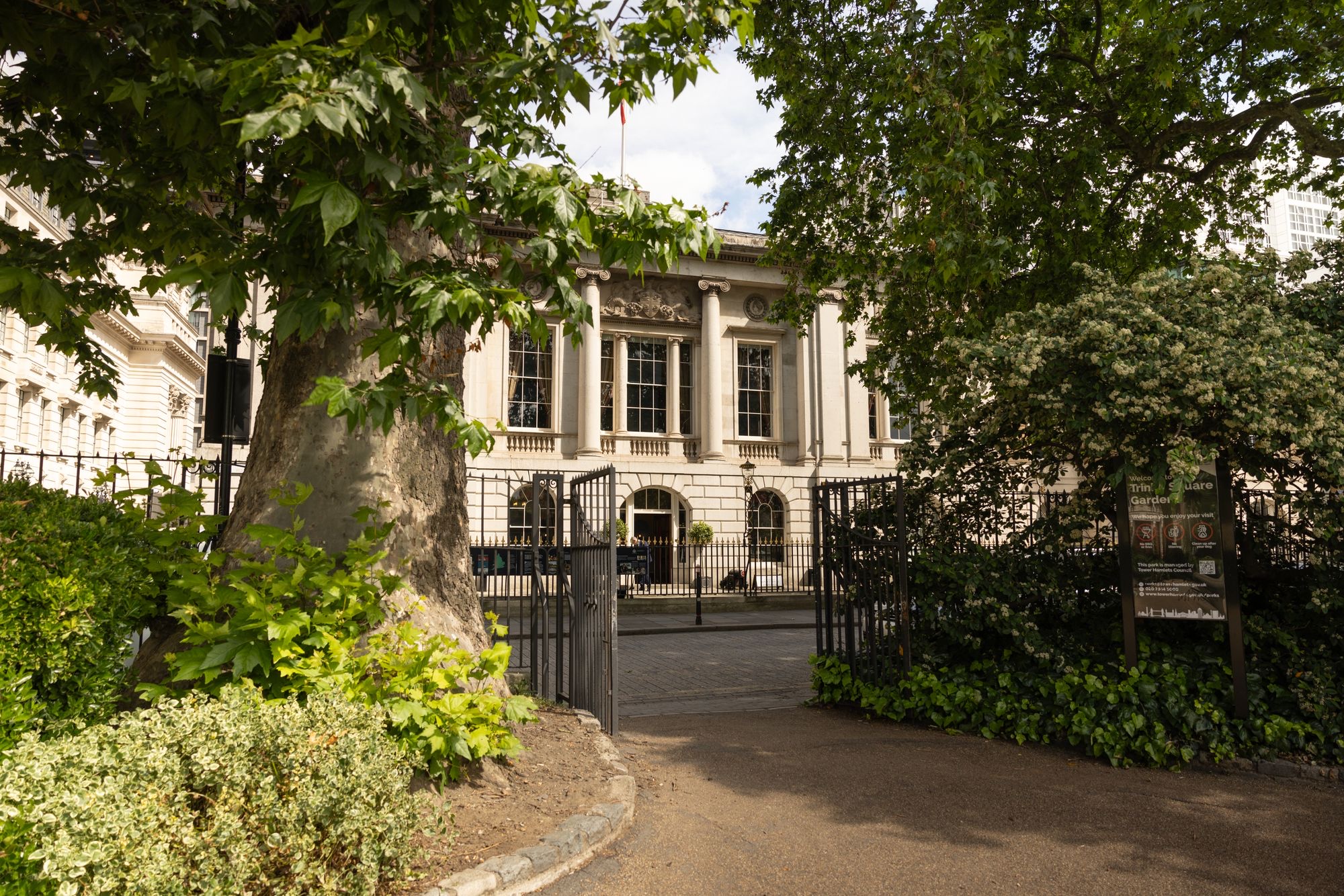 The house glimpsed through the plane trees and gates of Trinity Square Gardens, Trinity House on Tower Hill