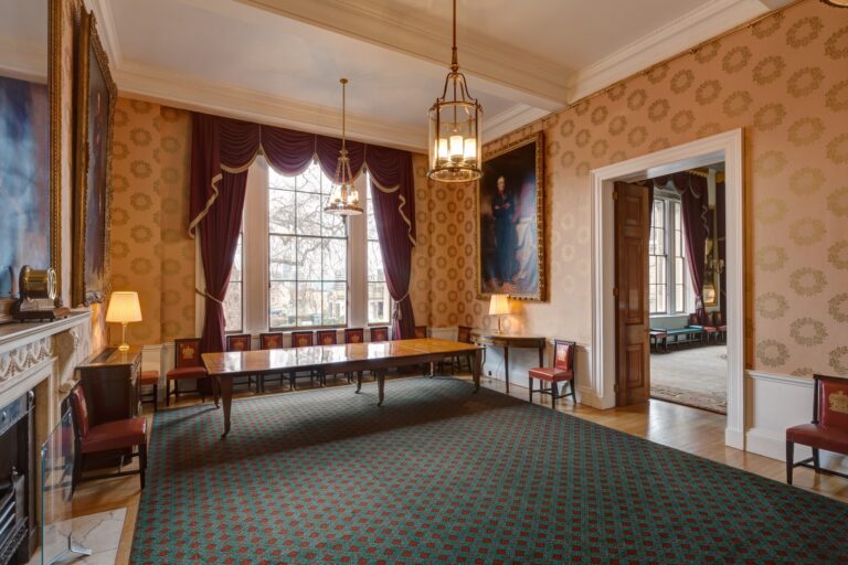 The Luncheon Room, with damask walls, a Georgian fireplace, portraits of former Masters and its long polished table, Trinity House on Tower Hill