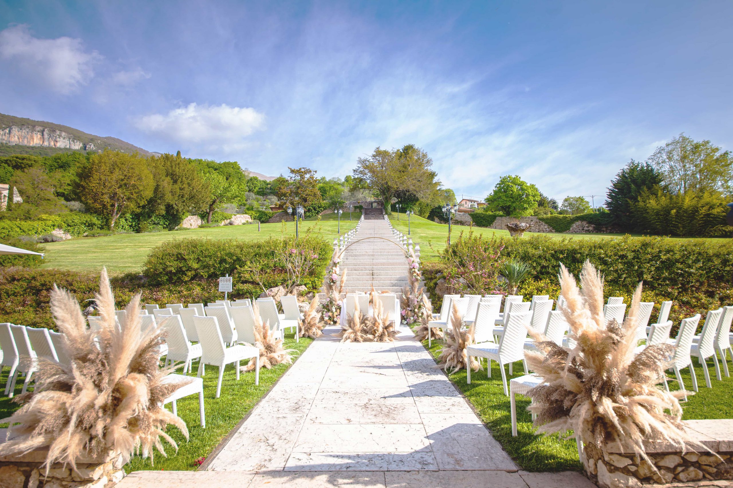 Chairs and pampas grass set for a ceremony in the Parco della Pieve, below the stone staircase, Villa Cariola