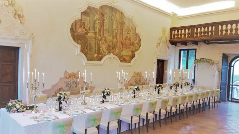 A frescoed hall with a balustraded gallery, laid with a long candlelit table, Villa Cariola