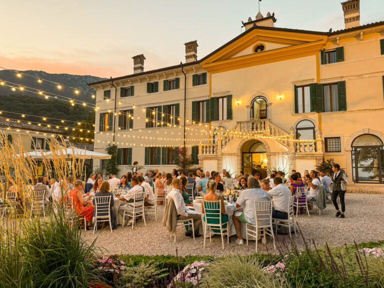 A wedding dinner in the courtyard at dusk under strings of lights, Villa Cariola