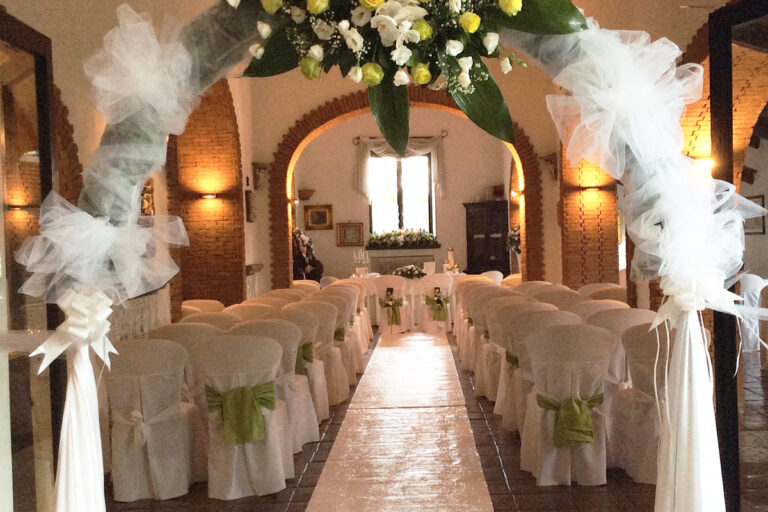 A ceremony layout in the indoor hall, framed by a floral arch under the brick arches, Villa del Vecchio Pozzo in Posillipo