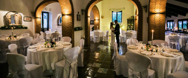 The indoor hall set with round tables between brick arches and tiled floors, Villa del Vecchio Pozzo in Posillipo