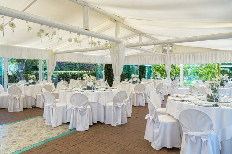 Round tables laid inside the large outdoor gazebo, open to the garden, Villa del Vecchio Pozzo in Posillipo