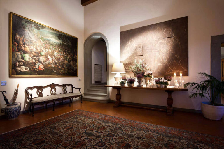 Salon with a large old master painting, carpet, antique bench and candlelit console, Villa Il Cerretino