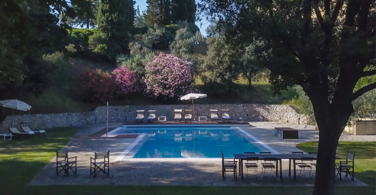 Pool in the garden with loungers and flowering shrubs, seen from under a tree, Villa Il Cerretino