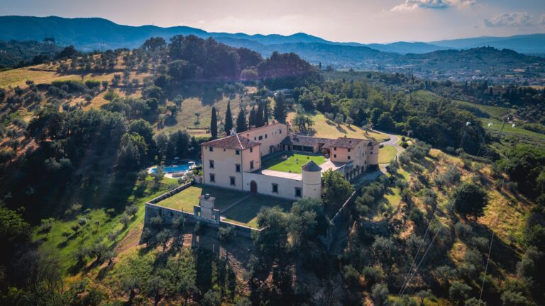 Aerial view of the villa on its hillside among olive groves, with hills and the plain beyond, Villa Il Cerretino