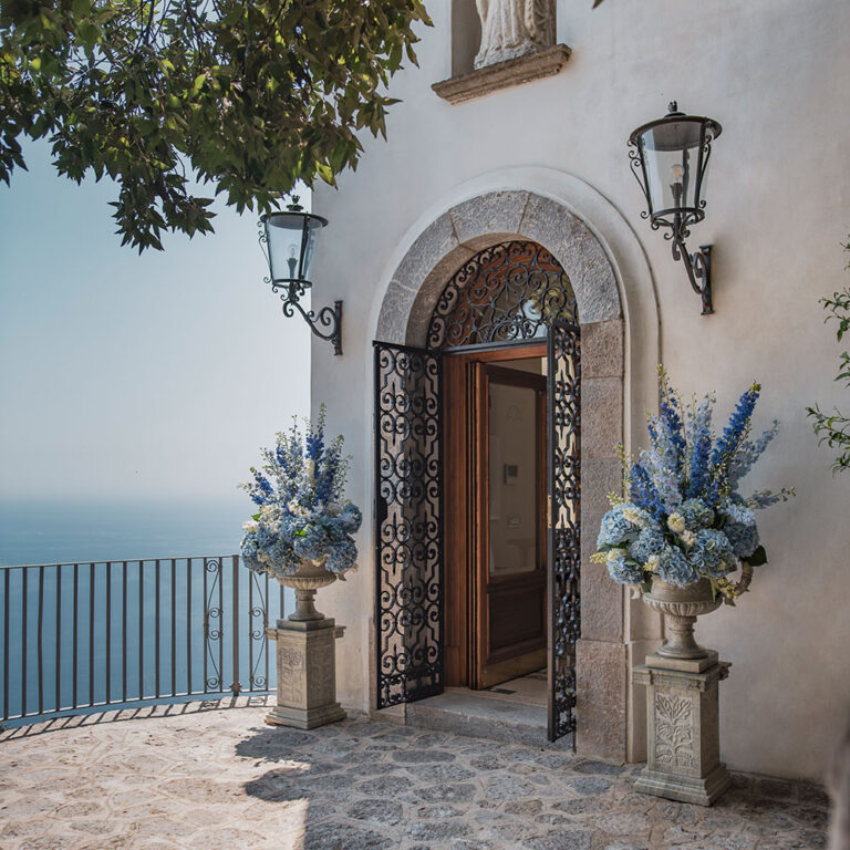The arched entrance door with iron gates, lanterns and urns of flowers, Villa La Rondinaia