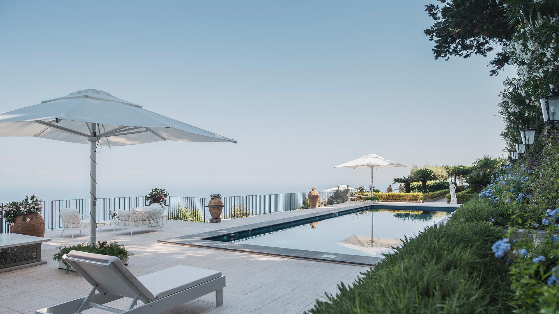 The pool terrace with parasols and loungers above the sea, Villa La Rondinaia