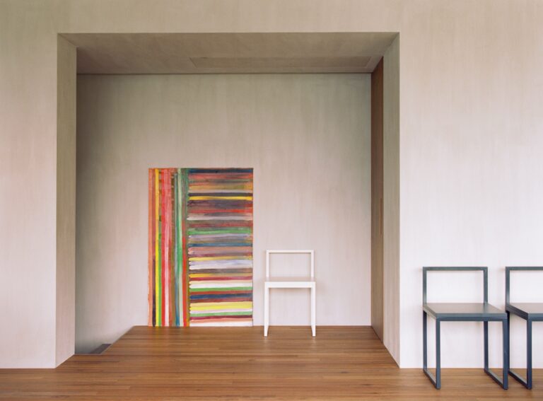A striped painting set in a recess, with simple chairs on a timber floor, Villa Nascosta