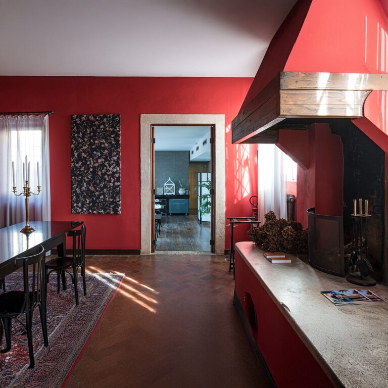 A red-walled room of the VI·OR restaurant, with a hooded fireplace and dark wooden tables, Villa Ormaneto