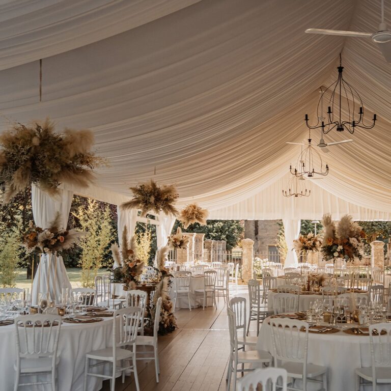 Round tables under the draped ceiling and chandeliers of the tensile structure in the park, Villa Ormaneto