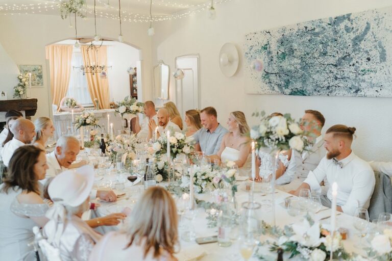 A wedding meal at one long table in a white-walled main room hung with a large blue abstract painting, Villa Sofia