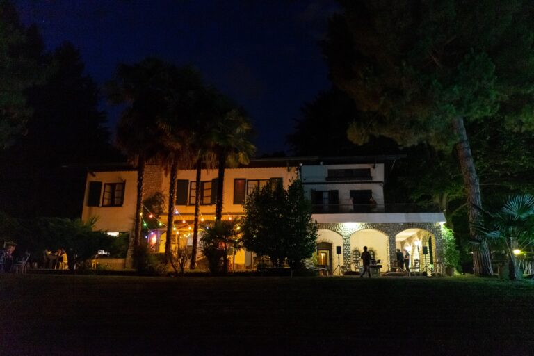 The villa and its arcaded ground floor lit up at night, seen from the lawn, Villa Sofia