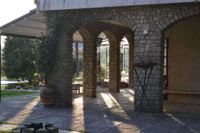 The stone-arched portico along the villa, in late sun, Villa Sofia