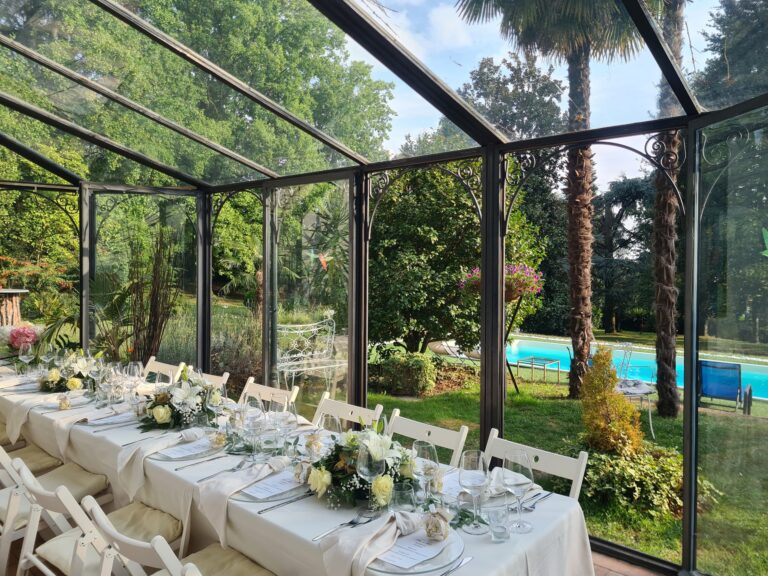 A long table dressed with flowers in the glass veranda, the pool beyond, Villa Sofia