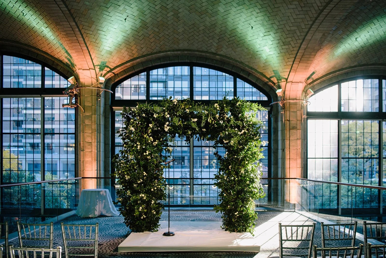 Ivy and white-flower ceremony arch before a tall arched window at Gustavino's, New York, 5th Avenue Weddings