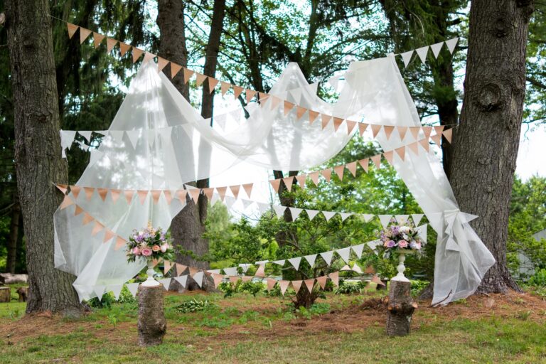 Ceremony canopy with bunting among trees at a country wedding, 5th Avenue Weddings