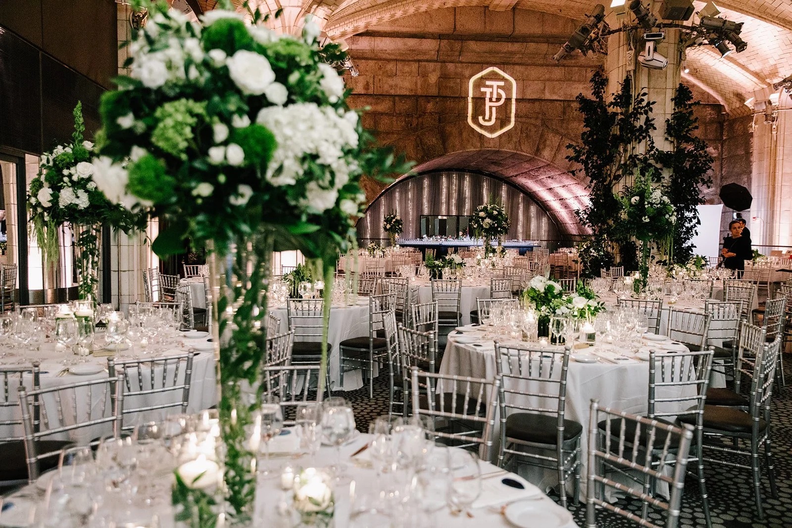 Round-table reception with tall white arrangements under the vaulted ceiling at Gustavino's, New York, 5th Avenue Weddings
