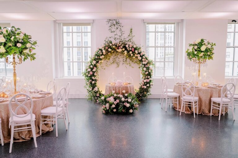 Circular floral arch and blush-draped tables in a Manhattan loft reception room, 5th Avenue Weddings