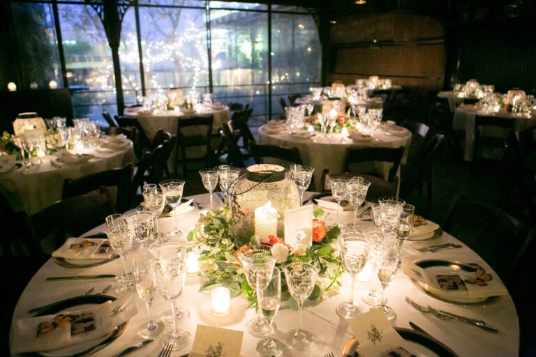 Candlelit round tables set with low floral centrepieces in a New York restaurant, 5th Avenue Weddings