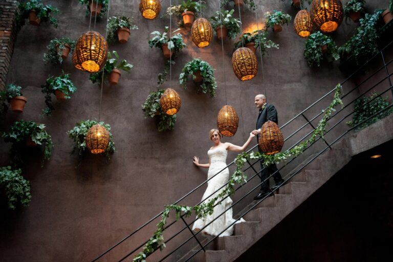 Couple on a staircase beneath hanging lanterns and planted walls at a New York restaurant, 5th Avenue Weddings