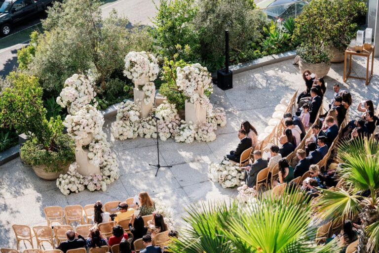 Rooftop ceremony with clusters of white flowers among palms, About Details Details