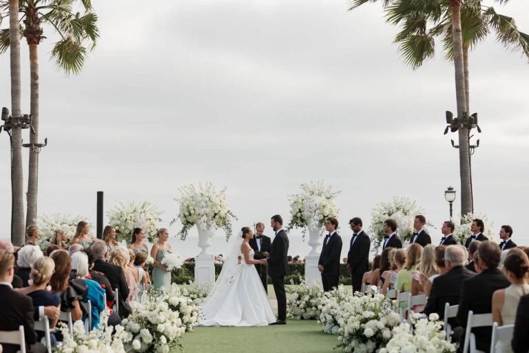 Oceanfront lawn ceremony between white flower arrangements, About Details Details