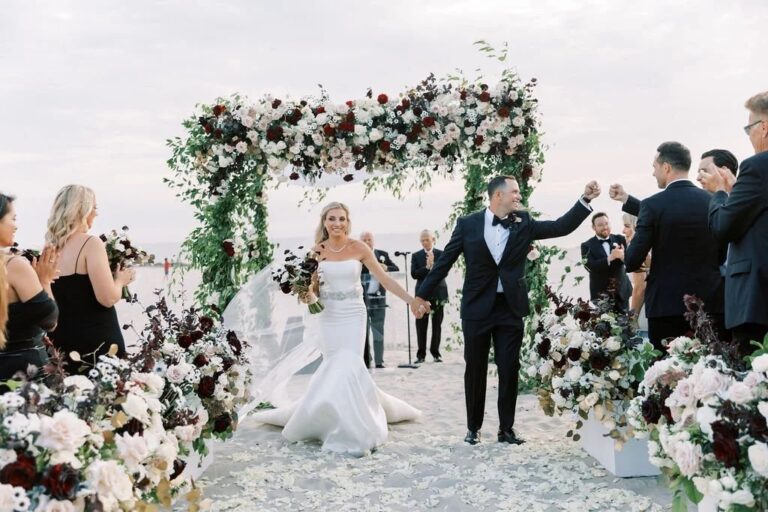 Couple walking back through a flower arch on the beach, About Details Details