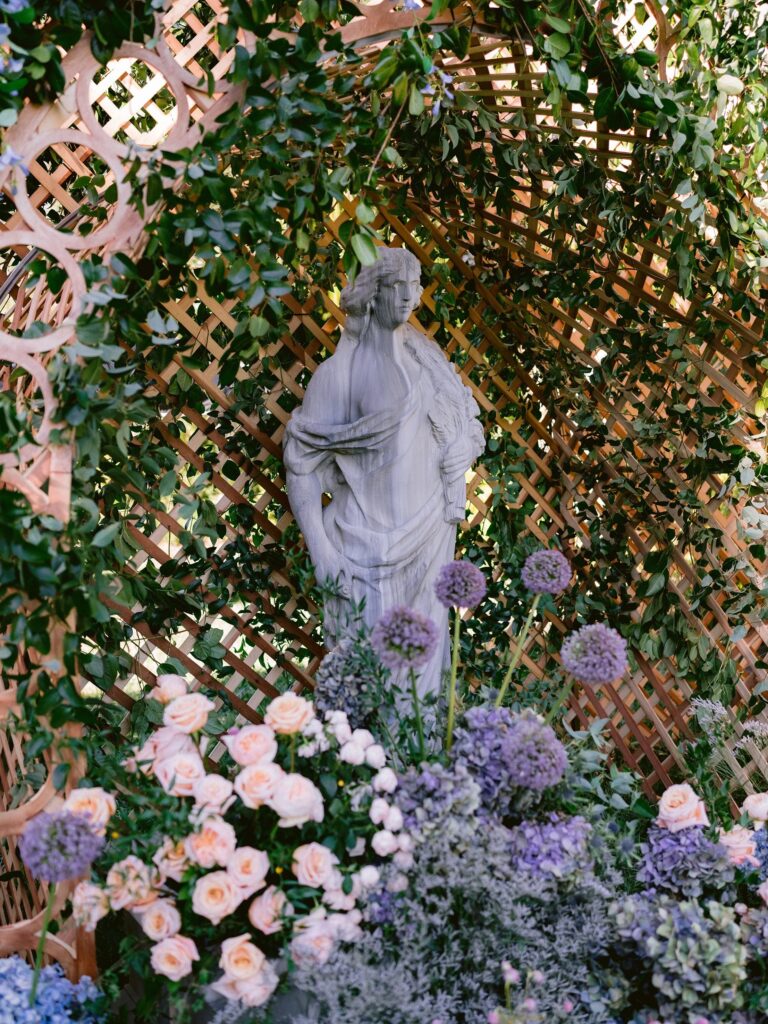 Garden statue framed by a lattice arbour and pastel flowers, About Details Details