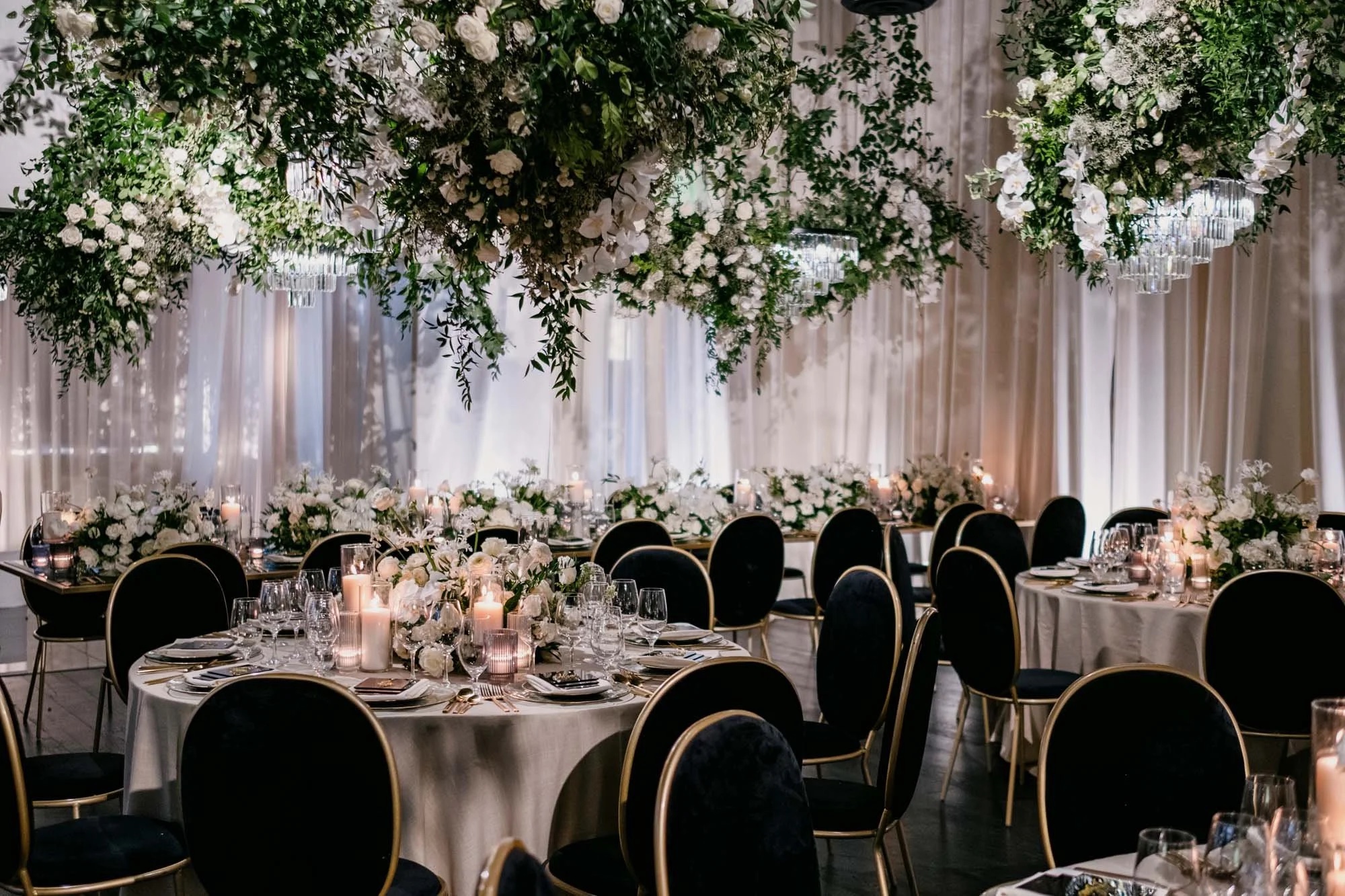 Round reception tables with candles under a canopy of hanging greenery and flowers, About Details Details